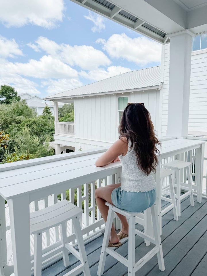 René sitting at the railing of a bright coastal balcony